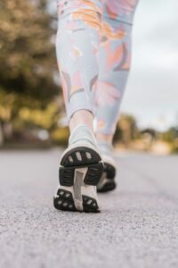 Adults of mixed ages walking together in activewear along a leafy paved park path in pleasant weather.