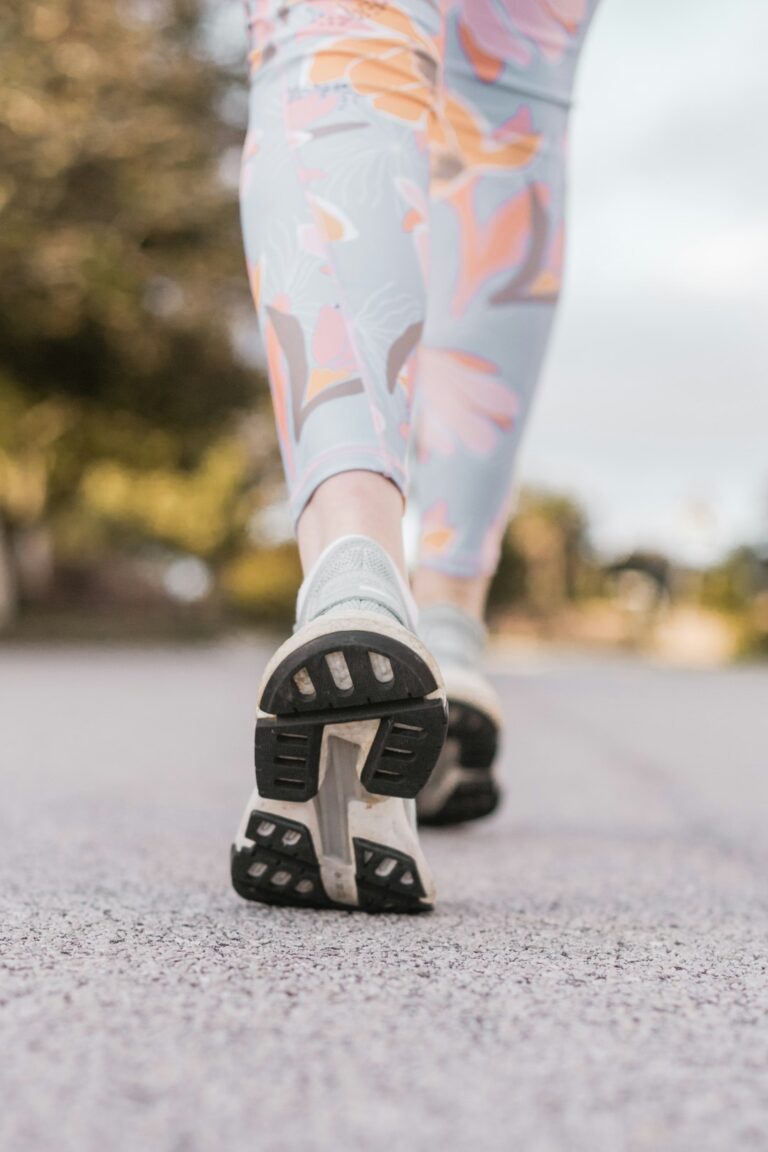 Adults of mixed ages walking together in activewear along a leafy paved park path in pleasant weather.